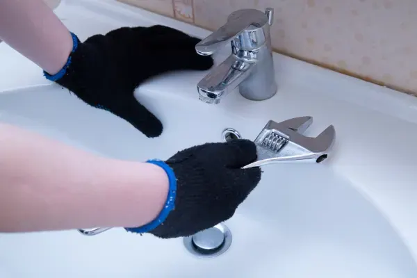 Plumber doing sink plumbing repair on a P-trap under a kitchen sink