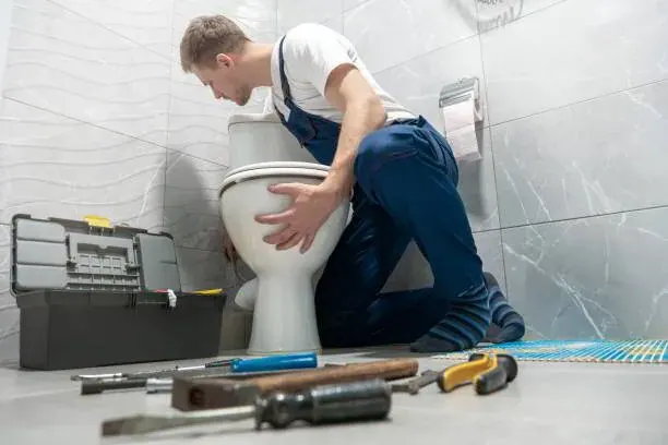 Plumber providing toilet repair services by replacing a fill valve in a toilet tank